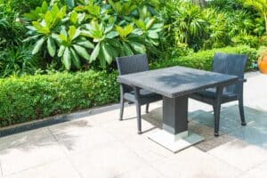 A garden scene featuring a table and two chairs on slab paving, perfect for outdoor relaxation.